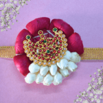 Eco-friendly rakhi with red rose petals, white jasmine buds, and ornate gold centerpiece on golden ribbon