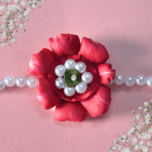 Eco-friendly rakhi featuring a red rose made of fresh petals with pearl-like center and green leaf, on a pearl bead strand