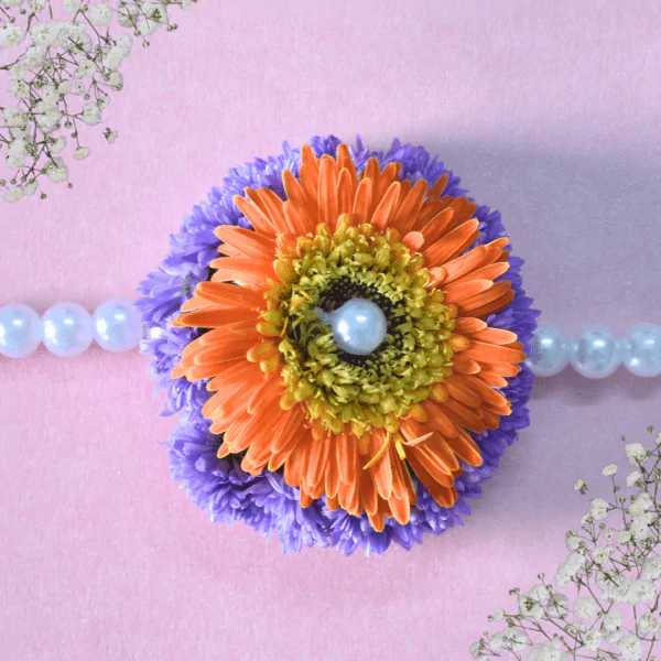 Handcrafted floral Rakhi with orange gerbera daisy, purple chrysanthemums, and pearl center