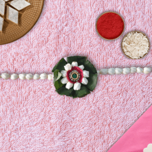 Eco-friendly floral rakhi with white jasmine buds, red rose center, green leaves, and jeweled centerpiece