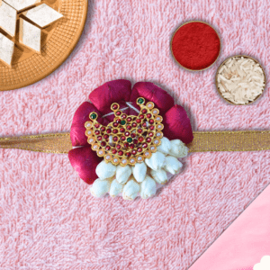 Eco-friendly rakhi with red rose petals, white jasmine buds, and ornate gold centerpiece on golden ribbon