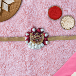 Eco-friendly rakhi with red rose petals, white jasmine buds, and ornate gold centerpiece on golden ribbon