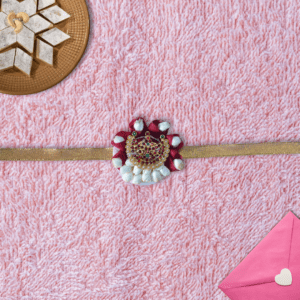 Eco-friendly rakhi with red rose petals, white jasmine buds, and ornate gold centerpiece on golden ribbon