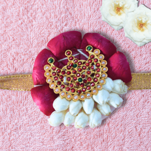 Eco-friendly rakhi with red rose petals, white jasmine buds, and ornate gold centerpiece on golden ribbon