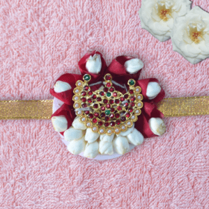 Eco-friendly rakhi with red rose petals, white jasmine buds, and ornate gold centerpiece on golden ribbon