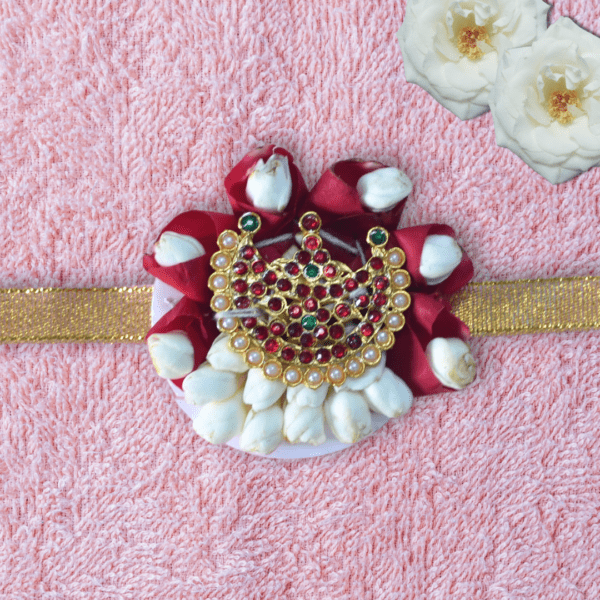 Eco-friendly rakhi with red rose petals, white jasmine buds, and ornate gold centerpiece on golden ribbon