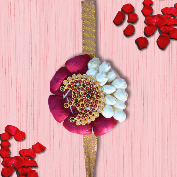 Eco-friendly rakhi with red rose petals, white jasmine buds, and ornate gold centerpiece on golden ribbon