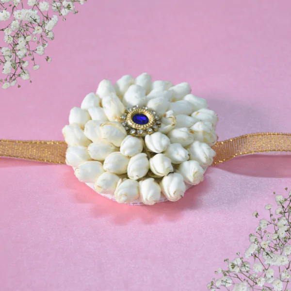 Eco-friendly rakhi made of white jasmine buds with blue gemstone center on golden ribbon,