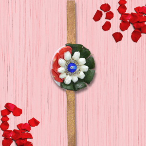 Eco-friendly rakhi featuring white jasmine buds, red rose petals, green leaves, and blue gemstone centerpiece on golden ribbon