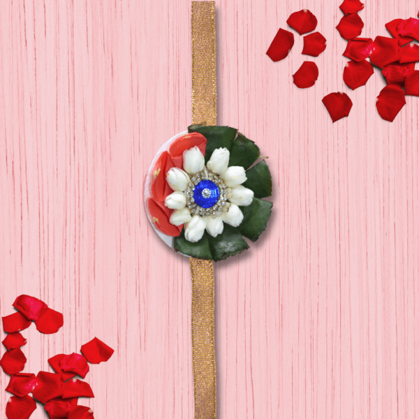 Eco-friendly rakhi featuring white jasmine buds, red rose petals, green leaves, and blue gemstone centerpiece on golden ribbon