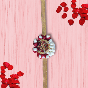 Eco-friendly rakhi with red rose petals, white jasmine buds, and ornate gold centerpiece on golden ribbon