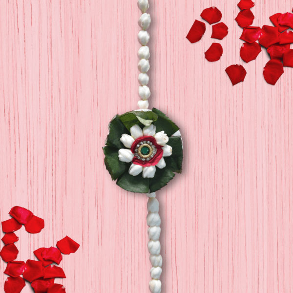 Eco-friendly floral rakhi with white jasmine buds, red rose center, green leaves, and jeweled centerpiece