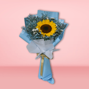 A beautiful bouquet featuring a large, vibrant sunflower surrounded by delicate baby's breath and greenery, wrapped in soft blue paper and tied with a shimmering gold ribbon.