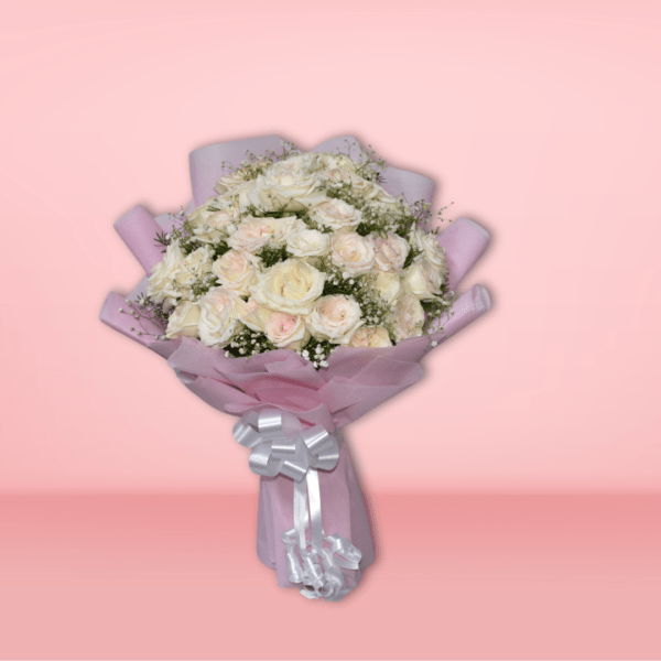 Elegant bouquet of white and blush roses with baby's breath, wrapped in pink paper with silver ribbon, on pink background