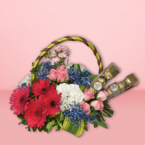 Flower basket with red gerberas, pink roses, white carnations, and Ferrero Rocher chocolates on a pink background.