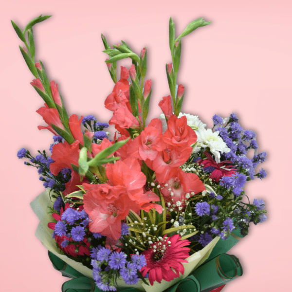 Mixed flower bouquet featuring pink gladiolus, chrysanthemums, and asters wrapped in green and red paper, perfect for gifting in Hyderabad.