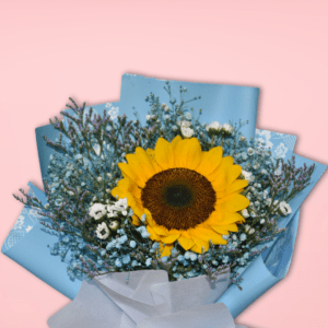 A beautiful bouquet featuring a large, vibrant sunflower surrounded by delicate baby's breath and greenery, wrapped in soft blue paper and tied with a shimmering gold ribbon.