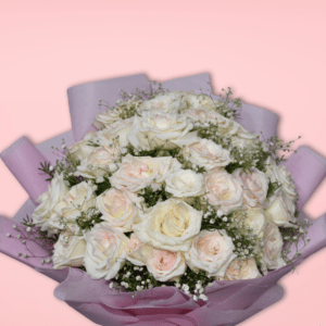 Elegant bouquet of white and blush roses with baby's breath, wrapped in pink paper with silver ribbon, on pink background