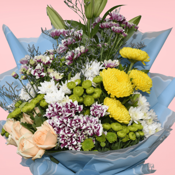 Mixed flower bouquet with yellow chrysanthemums, peach roses, white and purple carnations, wrapped in blue paper on a pink background.