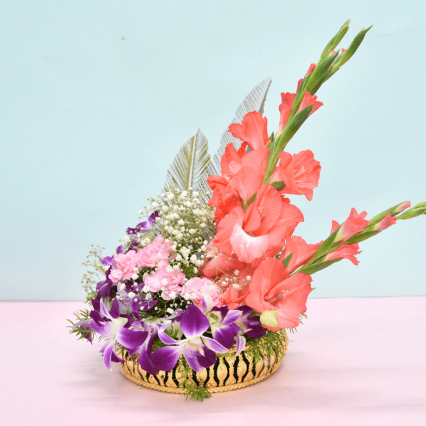 Tropical flower basket with coral gladioli, purple orchids, pink carnations, and silver feathers in a golden container