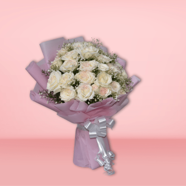 Elegant bouquet of white and blush roses with baby's breath, wrapped in pink paper with silver ribbon, on pink background