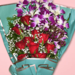 Mixed flower bouquet with red roses and purple orchids in teal wrapping