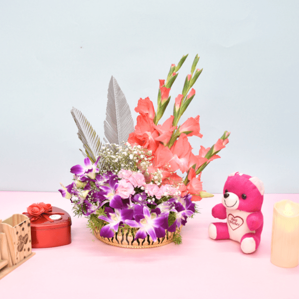 Tropical flower basket with coral gladioli, purple orchids, pink carnations, and silver feathers in a golden container