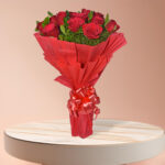 Luxurious bouquet of 20 red roses with green foliage in red wrapping