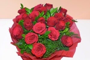 Luxurious bouquet of 20 red roses with green foliage in red wrapping