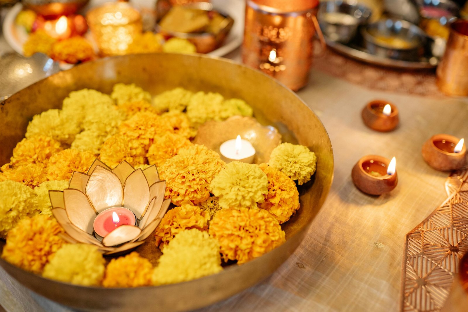 Marigold flowers decorated in a brass bowl with candles for home decoration