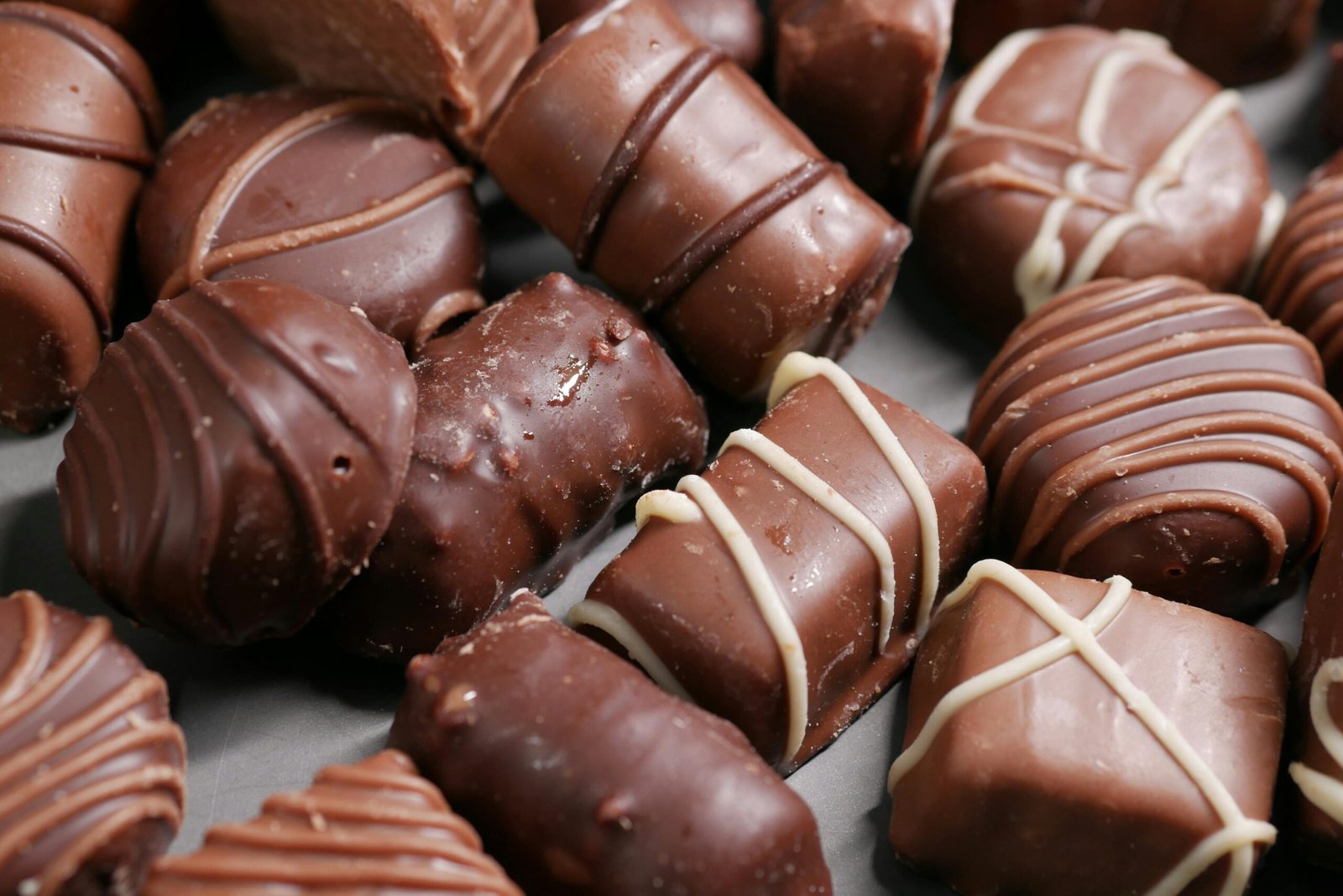 Assortment chocolates with smooth milk and dark chocolate coatings arranged closely together on a tray