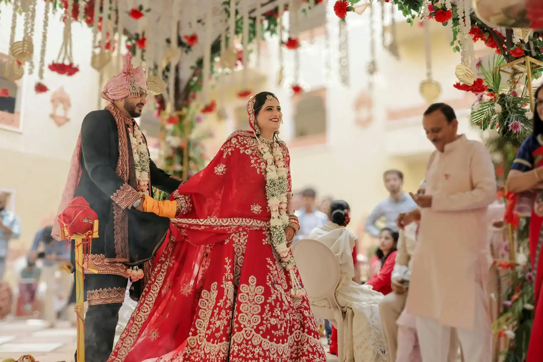 Indian wedding ceremony with bride and groom in traditional attire under floral decor