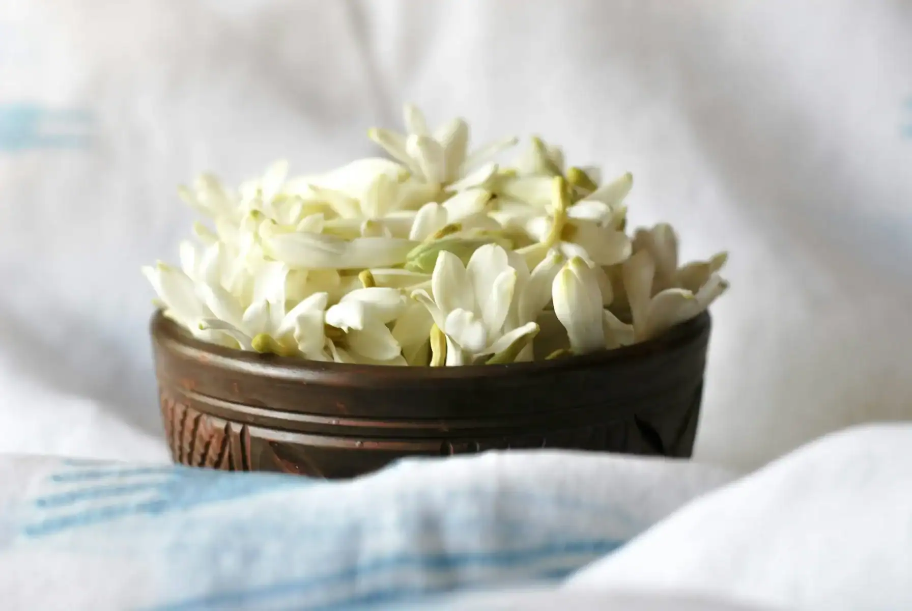 Fresh white tuberose flowers arranged in a rustic wooden basket, perfect for fragrant floral decor, weddings, and traditional flower arrangements.