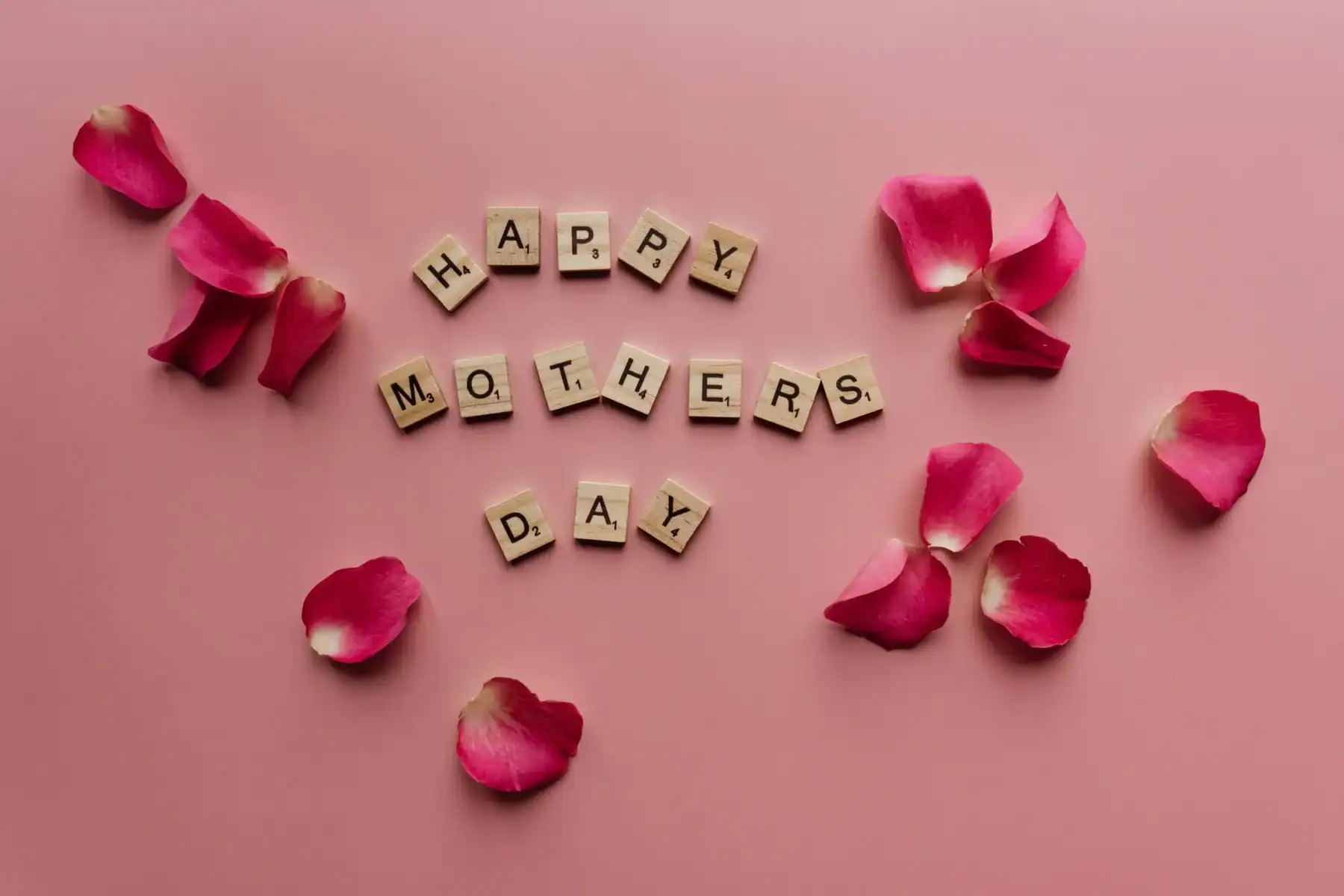 Happy Mother’s Day floral flat lay with pink rose petals and wooden letter tiles, elegant Mother’s Day flower greeting background for celebration, gifting, and floral decor.