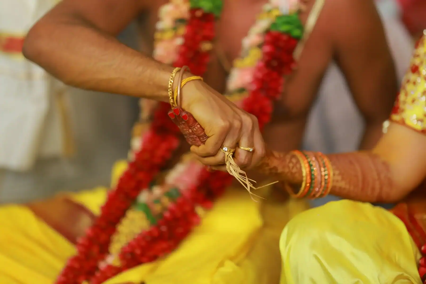 Couple holding hands during traditional Indian wedding vows