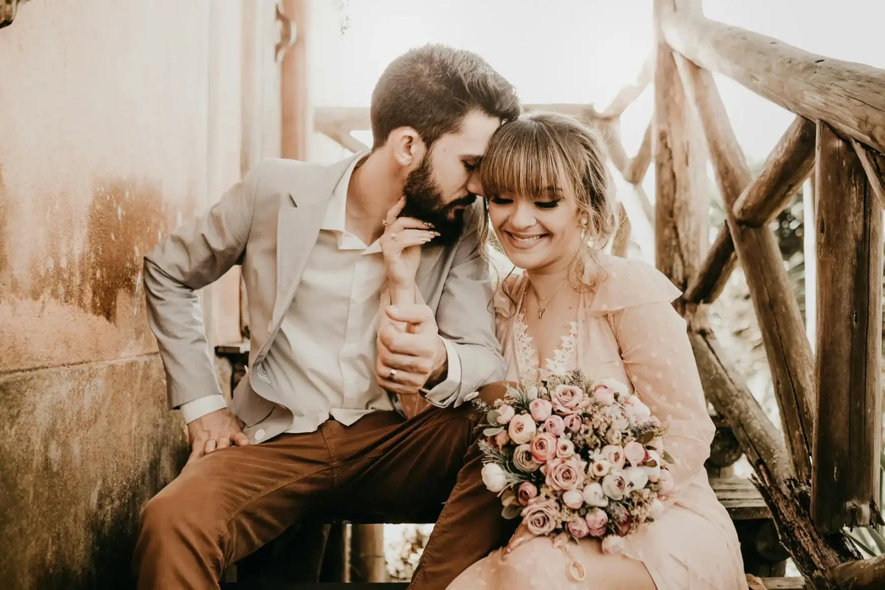 Romantic couple sitting together outdoors smiling with a blush pink and white rose bouquet, elegant pastel flower arrangement for weddings and anniversaries 